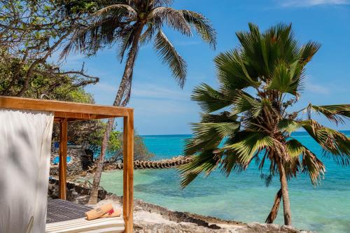 a hammock on a beach with two palm trees at Hotel San Pedro de Majagua in Isla Grande
