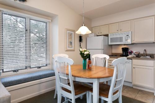 eine Küche mit einem Holztisch und weißen Stühlen und einem Tisch in der Unterkunft Stunning Condo with Beach Access The Shores 5719 in Traverse City