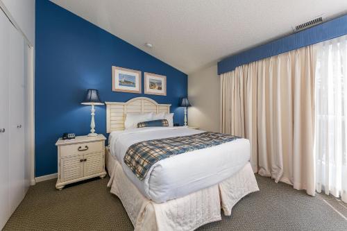 ein Schlafzimmer mit einem Bett und einer blauen Wand in der Unterkunft Stunning Condo with Beach Access The Shores 5719 in Traverse City