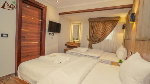 a hotel room with two beds and a television at Suzana Pyramids hotel in Cairo