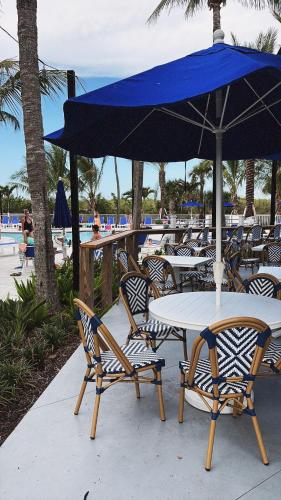 a table and chairs with a blue umbrella at a beach at Casa SolMar in Fort Pierce