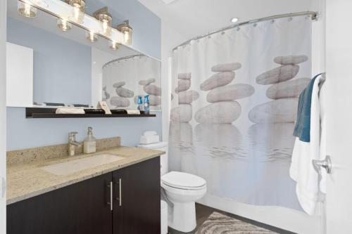 a bathroom with a shower curtain with a toilet and a sink at Urbanest - Spectacular Views & Amenities Parking in Calgary