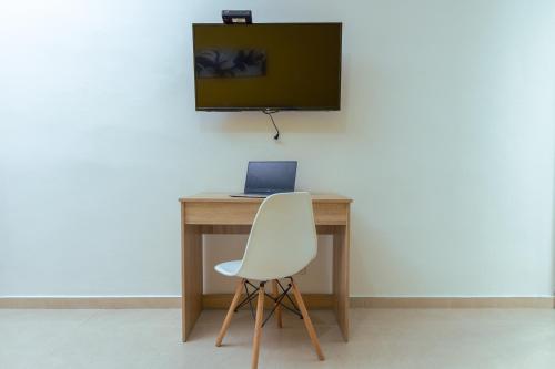 a white chair sitting in front of a desk with a laptop at HOTEL CATALUÑA - SOLUCIONES HOTELERAs in Pereira