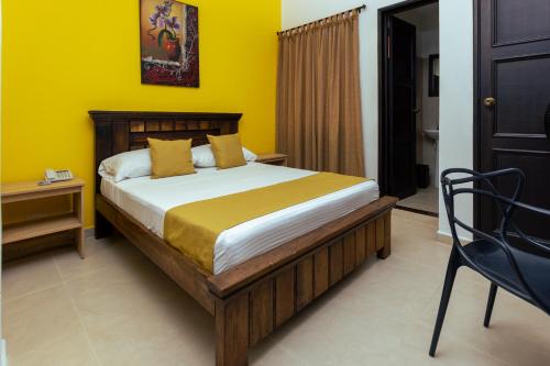 a bedroom with a bed with a yellow wall at HOTEL CATALUÑA - SOLUCIONES HOTELERAs in Pereira