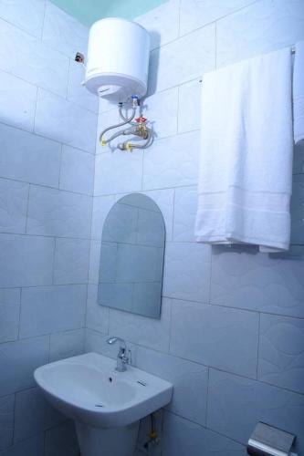 a white bathroom with a sink and a mirror at El RoI KADOSH Motel Kyenjojo in Kampala