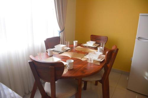 a dining room table with chairs and a table and a refrigerator at El RoI KADOSH Motel Kyenjojo in Kampala
