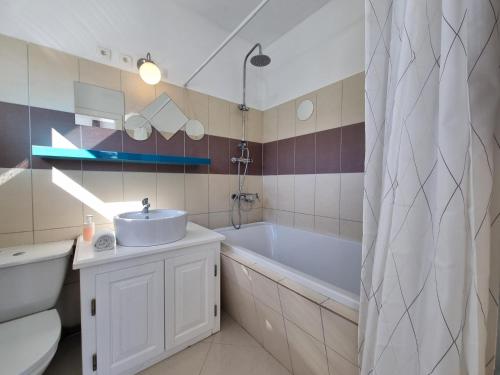 ein Badezimmer mit Badewanne und Waschbecken und einem Tubermottermott in der Unterkunft Clos des Oliviers in Oupia