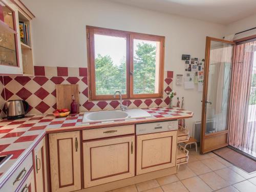 une cuisine avec un évier et une fenêtre dans l'établissement La Bergeronnette, à Tourtour