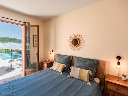 - une chambre avec un lit bleu et une porte coulissante en verre dans l'établissement La Bergeronnette, à Tourtour