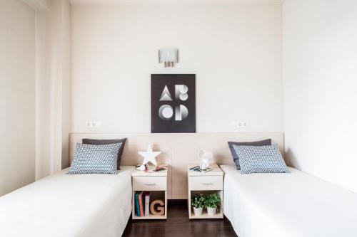 2 łóżka w pokoju z białymi ścianami w obiekcie Residencia Universitaria Giner de Los Ríos w mieście Alcalá de Henares