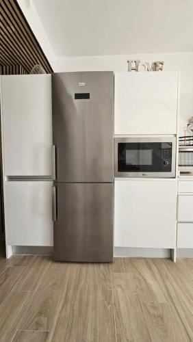 a kitchen with a stainless steel refrigerator and white cabinets at Adosado en Zahara de los Atunes (Atlanterra) in Zahara de los Atunes