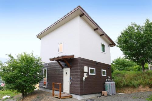 a small house with a white and brown at Hill House B NakaFurano Hokkaido JAPAN in Nakafurano