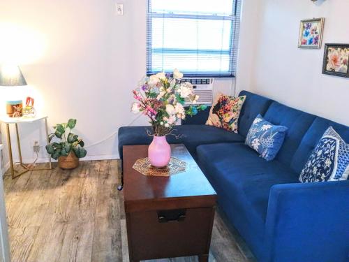 a living room with a blue couch and a vase with flowers at Explore New York from Queens in Queens
