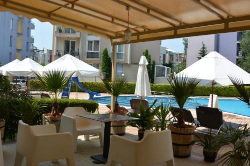 een terras met een tafel en stoelen en een zwembad bij Rainbow 1 Holiday Complex in Sunny Beach