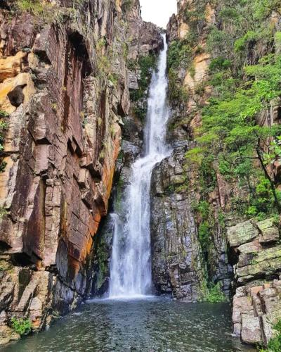 a waterfall in a canyon with a pool of water at Pousada Rio Cipó in Serra do Cipo