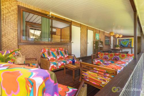 a living room with colorful couches and a table at Room 3 - Secluded shared Rustic Bungalow by Tipaniers Beach in Iumaru