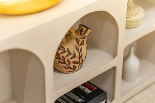 a shelf in a white cabinet with a vase at Babylone Appart & Pool, Hivernage in Marrakech