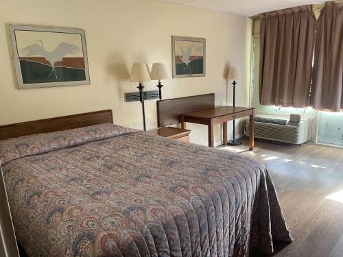 a hotel room with a bed and a desk at Tyler Inn & Suites in Tyler