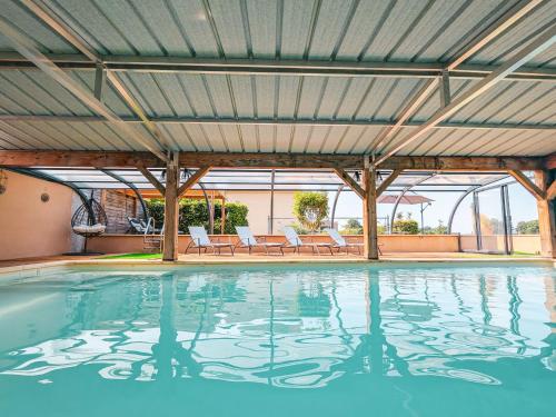 une piscine intérieure avec des chaises et un toit dans l'établissement Maison de charme en Berry près d'un golf & spa, jardin d'hiver, vélos, animaux bienvenus - tout inclus - FR-1-591-332, à Pouligny-Notre-Dame