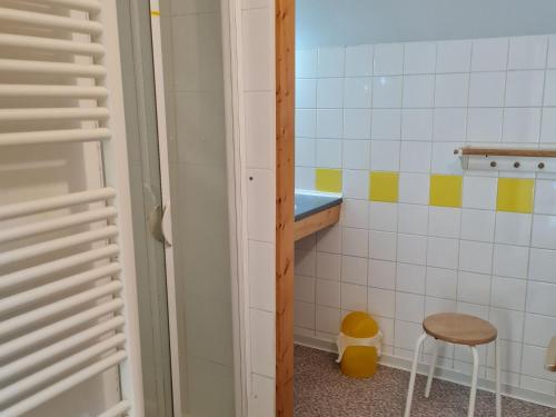 a small bathroom with a stool and a tiled wall at Gîte chaleureux au bord d'un ruisseau avec grand jardin, proche Metz et Nancy - FR-1-584-64 in Vandières