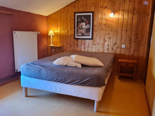 a bed in a room with a wooden wall at Gîte chaleureux au bord d'un ruisseau avec grand jardin, proche Metz et Nancy - FR-1-584-64 in Vandières