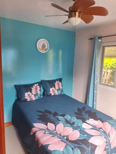 a bedroom with a bed with a blue wall and a ceiling fan at Maina Lodge in Avatoru