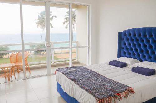a bedroom with a blue bed and a view of the ocean at Luxury Beachfront Apartment in Wattala