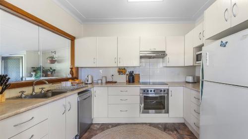 a white kitchen with white cabinets and a sink at Margarets Place - Character Filled Cottage In Heart Of Gloucester in Gloucester