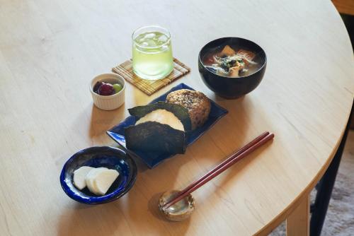a table topped with bowls of food and a glass of milk at Yanagawa Guesthouse HORIWARI 柳川の観光エリアにある静かな日本のゲストハウス in Yanagawa