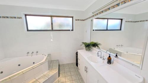 a white bathroom with a tub and a sink at Collingwood Lodge by Experience Jervis Bay in Vincentia