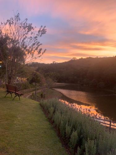 eine Parkbank neben einem Fluss bei Sonnenuntergang in der Unterkunft Pousada Shangri-lá in Cunha