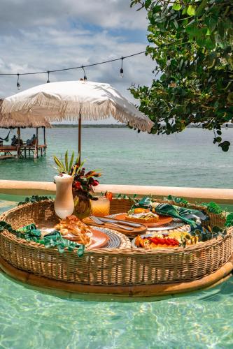 a table in the water with food and an umbrella at Khaban Bacalar Hotel Boutique in Bacalar