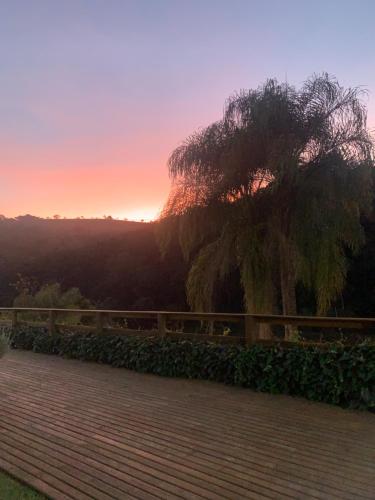 a tree sitting next to a fence at sunset at Pousada Shangri-lá in Cunha