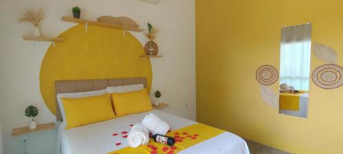 a bedroom with yellow walls and a bed with towels at Chalés da Cris in Fortim