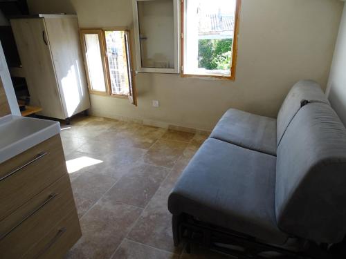 un salon avec un canapé et deux fenêtres dans l'établissement L'essentiel, Arles, à Arles