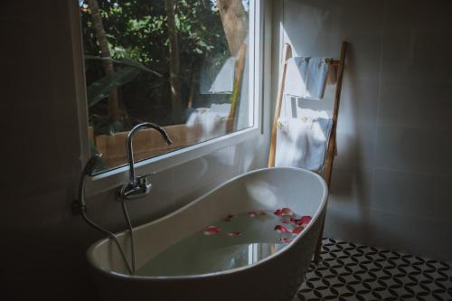 a bath tub in a bathroom with a window at Charm Hon Rom Villas Resort in Ấp Long Sơn