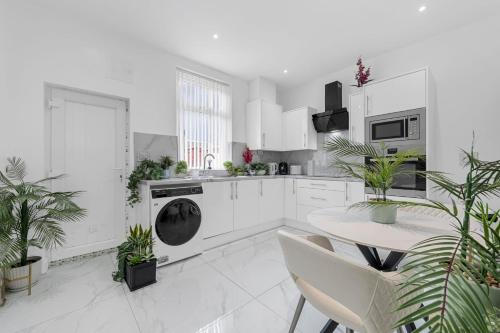 a kitchen with white cabinets and a table with plants at SLUXE Properties 4mins to Etihad Stadium and Coop live in Manchester