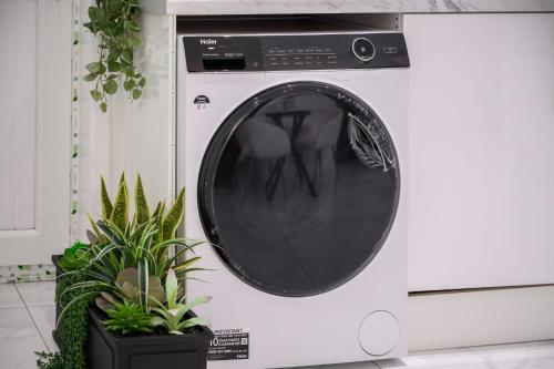 a white washing machine in a kitchen with plants at SLUXE Properties 4mins to Etihad Stadium and Coop live in Manchester