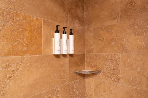 a shower with two white bottles on the wall at Prestige Radium Hot Springs Resort, WorldHotels Crafted in Radium Hot Springs