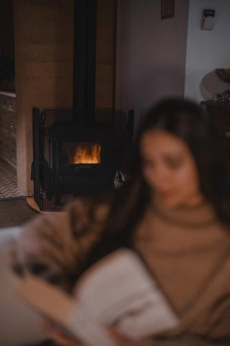 a woman reading a book in front of a fireplace at Stirling Creek Cottage in Stirling