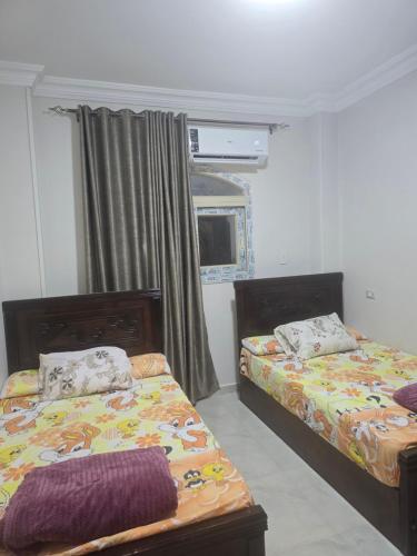 a bedroom with two beds and a window at Sedra Beautiful House in Madinat Al Ashir min Ramadan