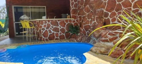 a swimming pool in front of a stone wall at Chalés da Cris in Fortim