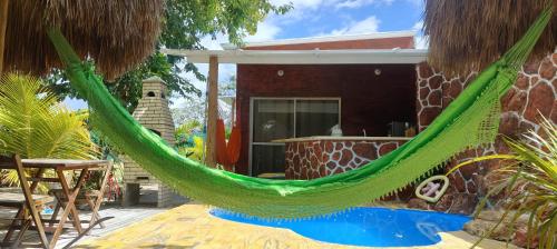 a green hammock in front of a house at Chalés da Cris in Fortim