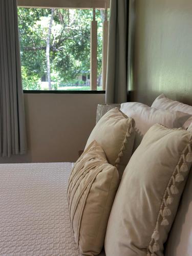 a group of pillows on a bed with a window at Hotel Diriá Santa Cruz in Santa Cruz