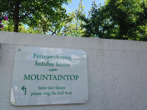 a sign on a white wall with trees in the background at Ferienwohnung Mountaintop in Lienz