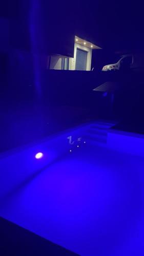 une pièce sombre avec une lumière bleue et une maison dans l'établissement La Villa du Silence Ouvrier, à Saint-Martin-d'Uriage