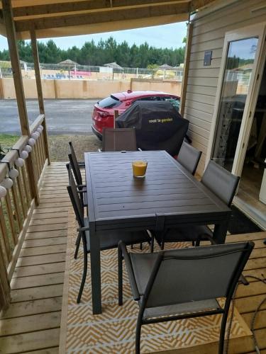une table et des chaises sur un porche avec une voiture garée dans l'établissement LES OYATS 4 ETOILES MOBIL HOME PRESTIGE 5 Personnes, à Seignosse