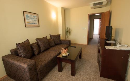 a living room with a brown couch and a table at Hotel Divesta - self check in in Varna City