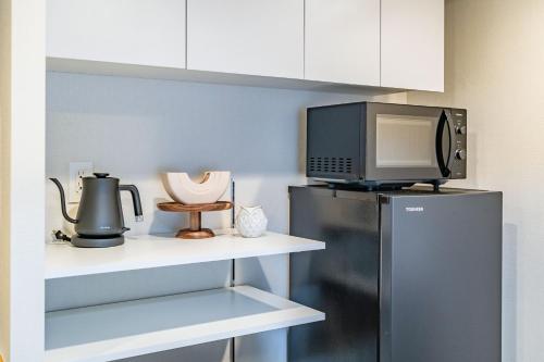 a kitchen with a black refrigerator and a microwave at Apartment Hotel 11 Higashi Umeda in Osaka