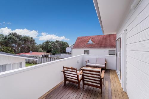 a balcony with two chairs and a table at TANG115A - Tangaroa Shores in Whangamata